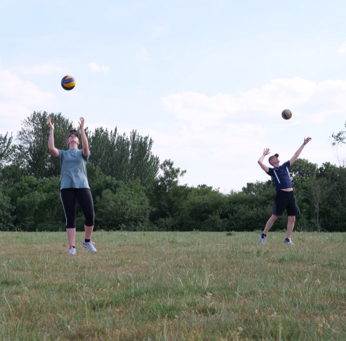 Two players setting the ball up into a bright sky